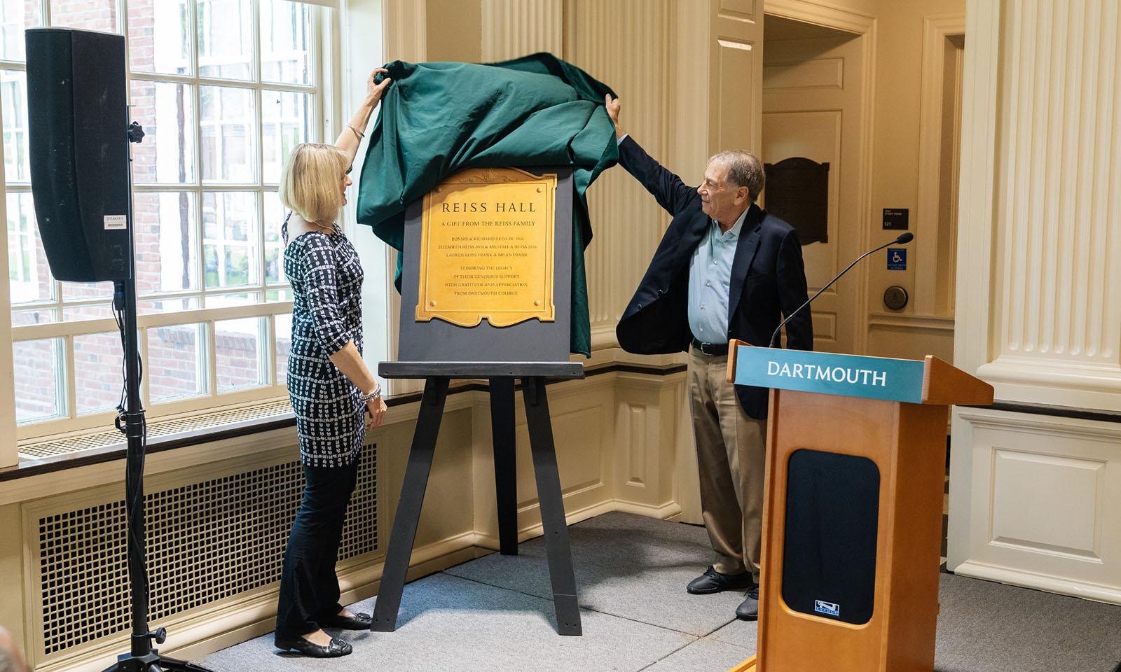 Two people unveil a sign on an easel