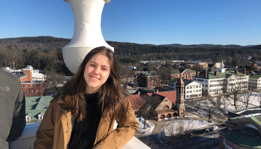 Woman standing against a railing with Dartmouth campus in the background