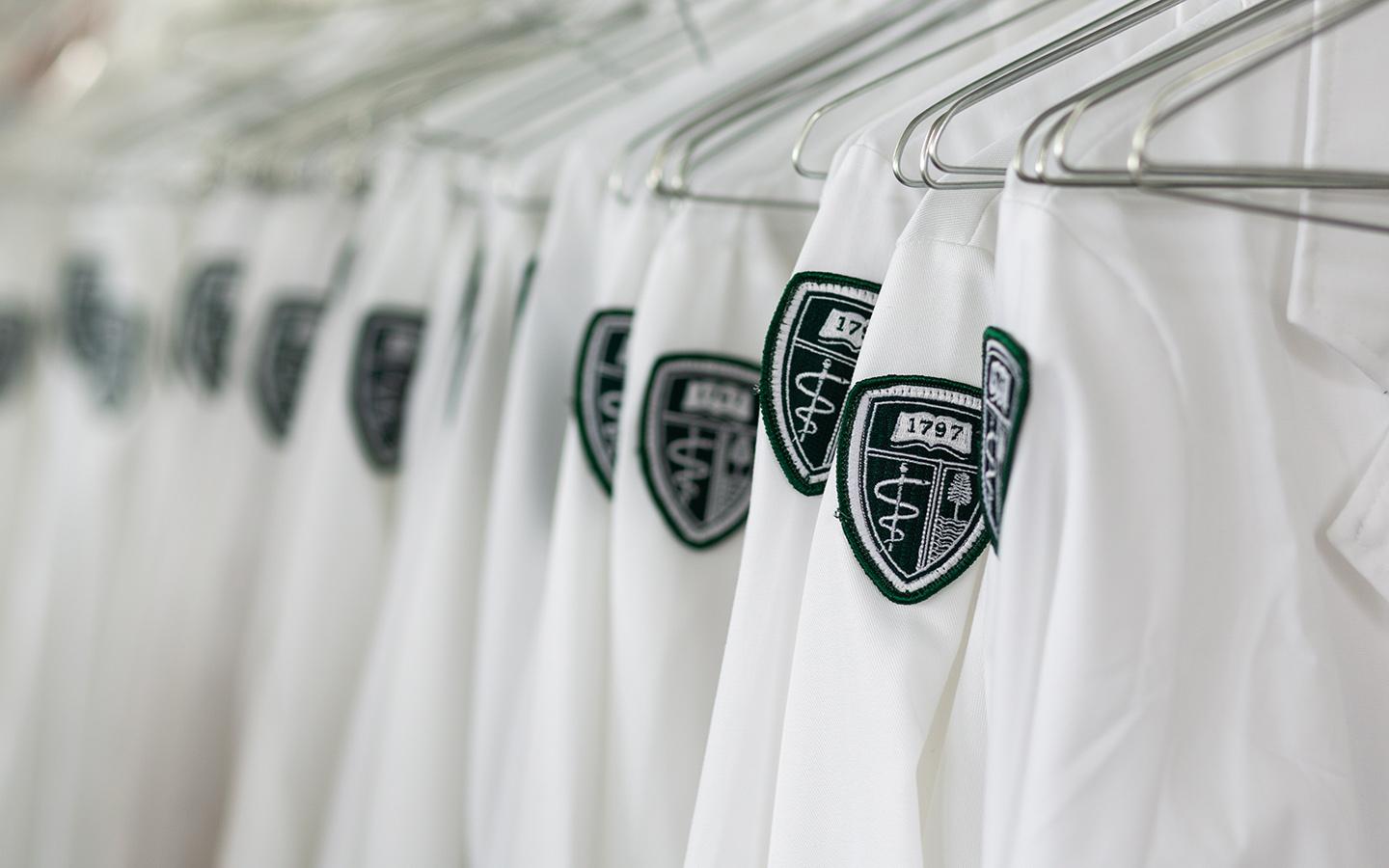 A close up of the Geisel shield on white coats on hangers