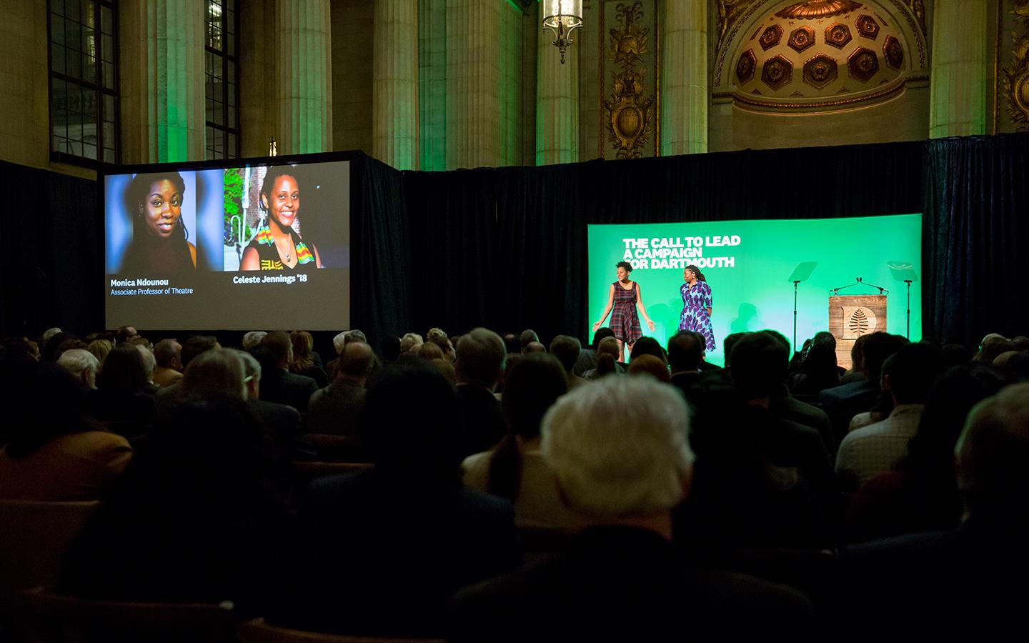 Two women on stage in front of a Dartmouth green screen