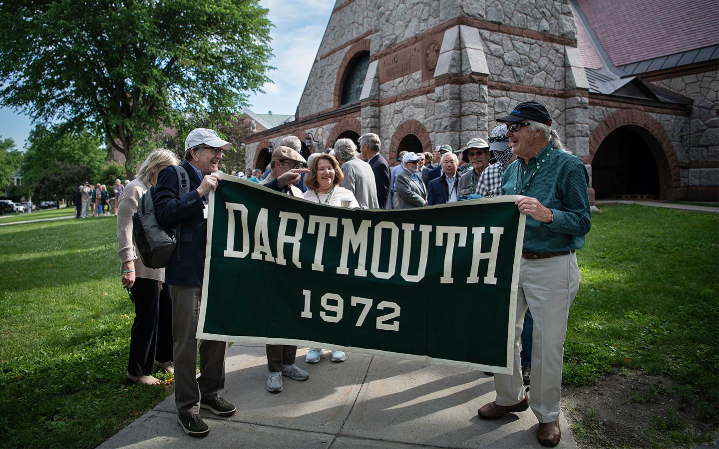 Members of the class of 1972 hold the class banner as they prepare to walk into commencement with the class of 2022