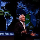 Jeff Immelt stands in front of a large screen showing a map of the world, overlaid with phrases about clean energy