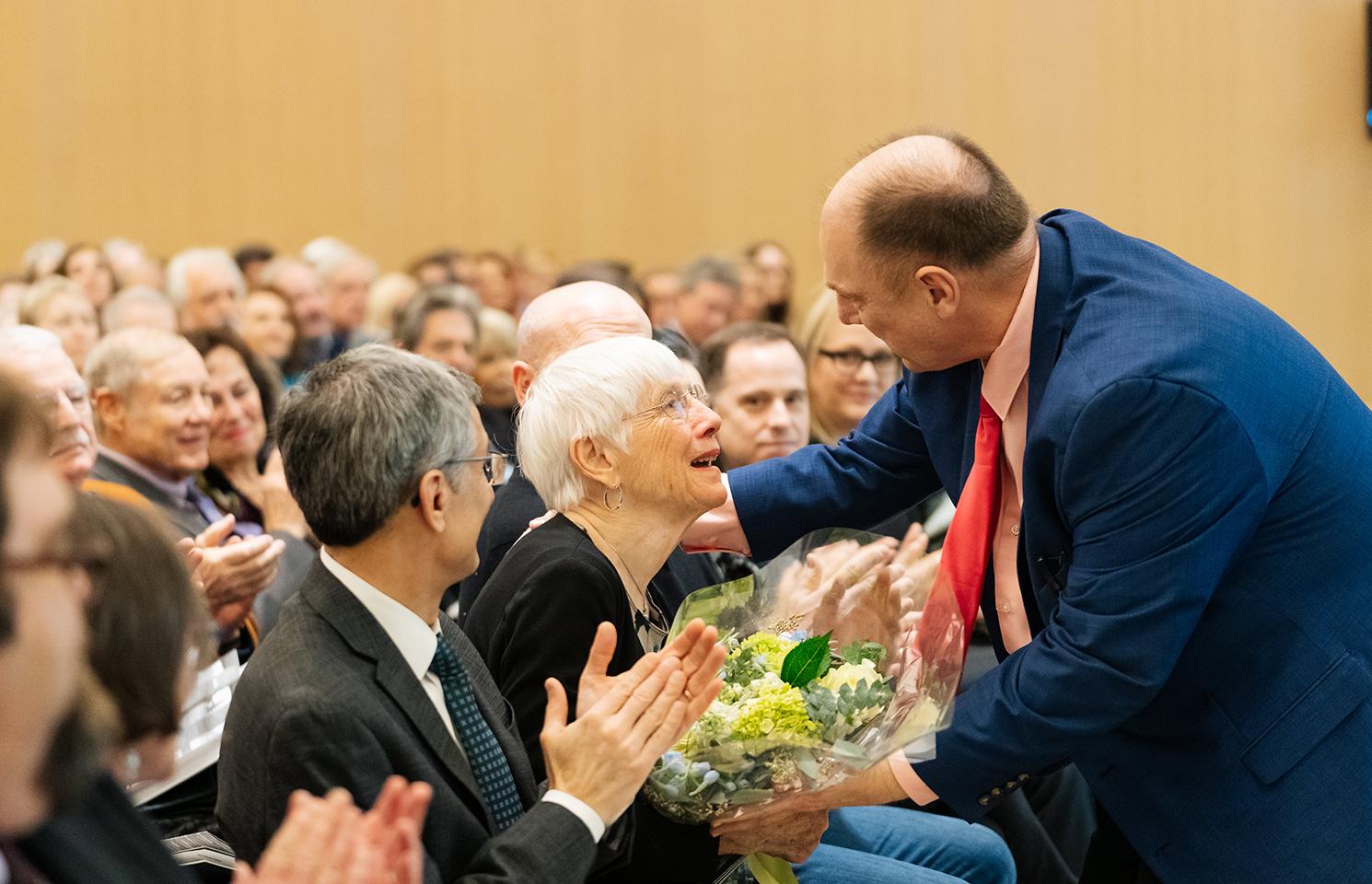A man presents a bouquet of flowers to a smiling woman.