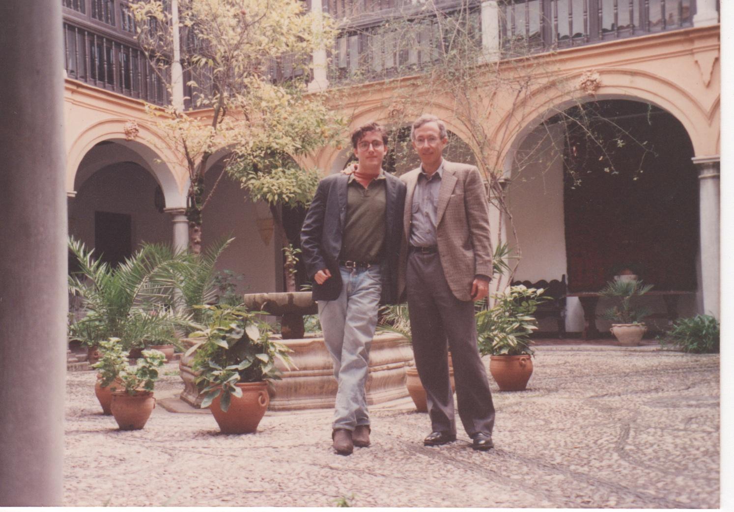 Two men stand in a Spanish courtyard.