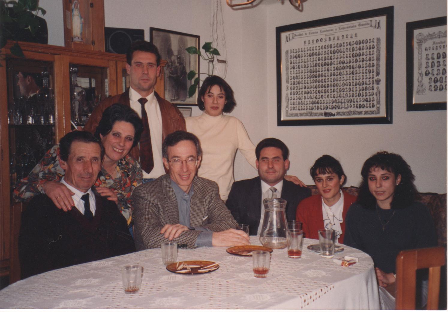 A group of people in semi-formal attire pose behind a dining table.