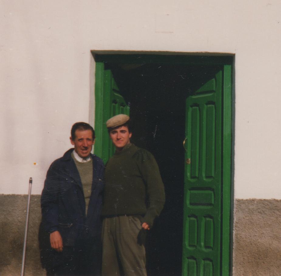 Two men pose in front of a green door.