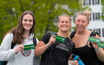 Students holding "Thank You" candy bars at the Dartmouth letters on the Green