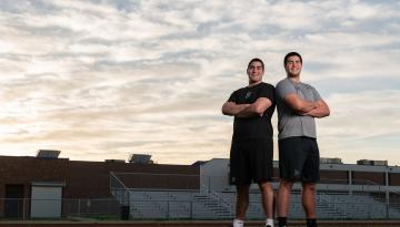 John Flores '22 and Michael Flores '23 standing on a football field