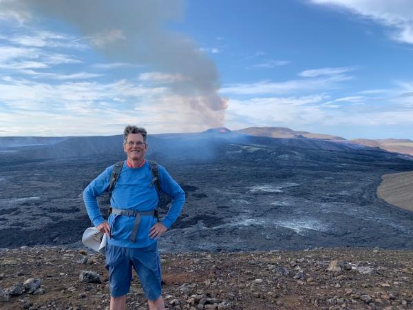 A man in a blue sweater standing in front of a volcano in Iceland